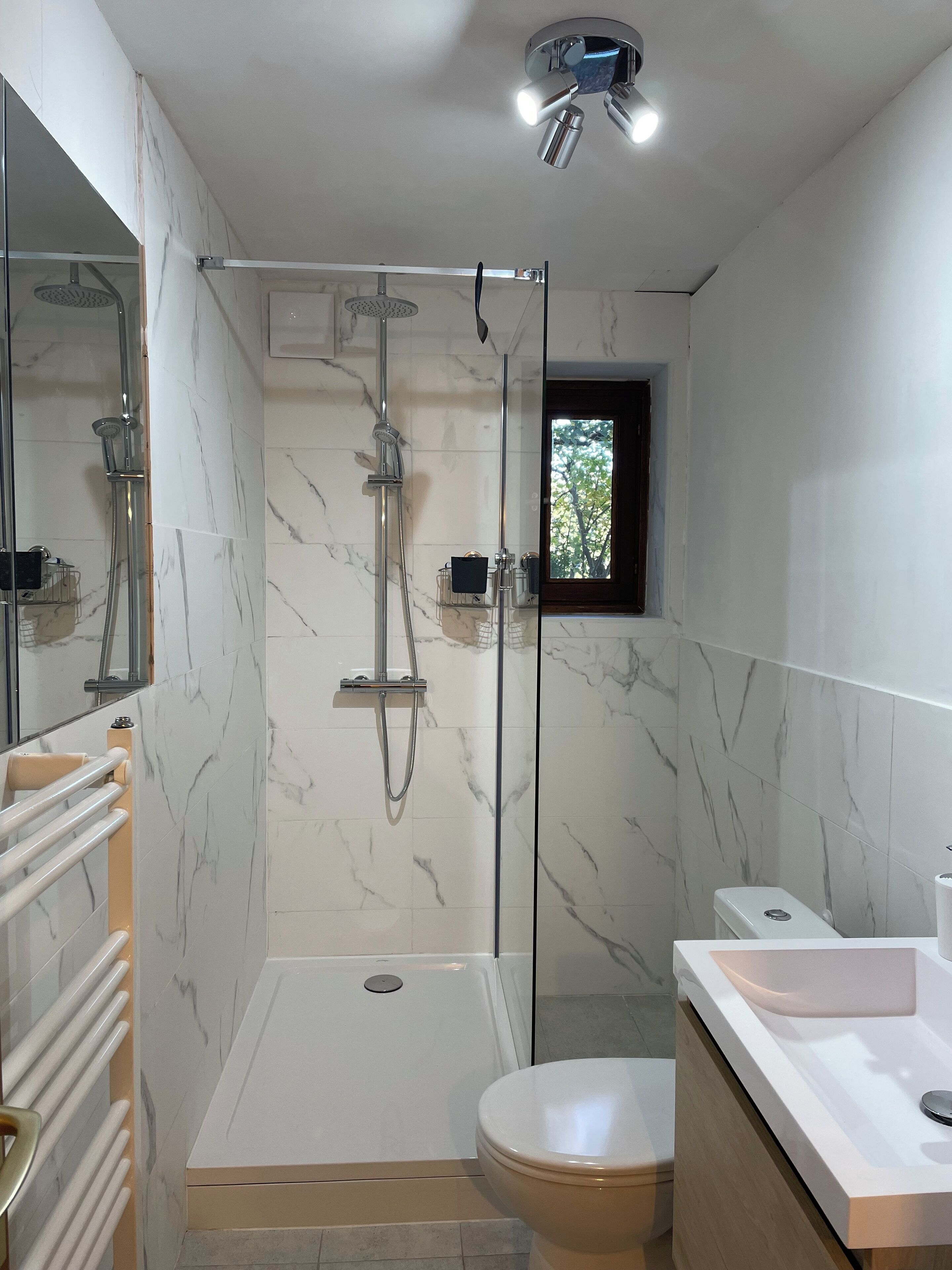 Une salle de bain moderne avec une douche à l’italienne, des toilettes et un lavabo.