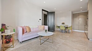 A modern living room with a sofa, a coffee table, and a dining area with chairs. - Brampton Grove Cozy Apartment - London (London)