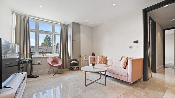 A modern living room with a pink sofa, a round coffee table, and a drum set. - Brampton Grove Cozy Apartment - London (London)