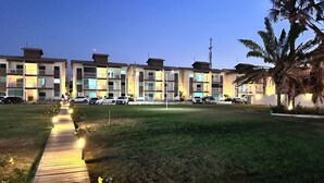 A multi-story hotel with a central courtyard, a paved walkway, and a parking area. - Apartment with river view (Barreirinhas)