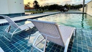 A swimming pool with two lounge chairs, a tiled deck, and a clear sky with clouds. - Apartment with river view (Barreirinhas)