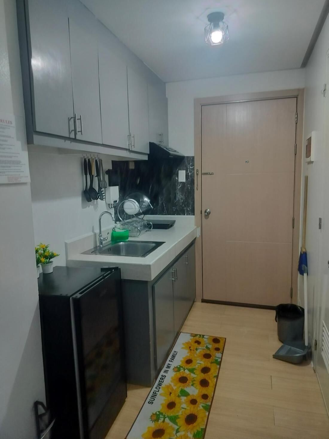 A compact kitchen with a sink, cabinets, and a refrigerator.