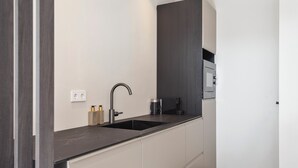 A modern kitchen with a black countertop, a sink, and a built-in oven.