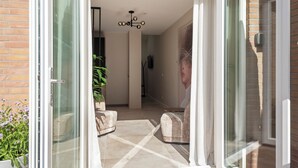 A modern interior with a glass door leading to a balcony, a potted plant, and a seating area.