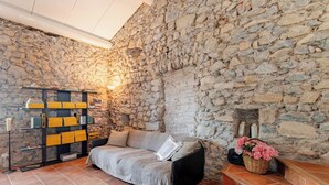 Ein gemütliches Zimmer mit Steinwand, einer Couch, einem Bücherregal und einem Blumenkorb.