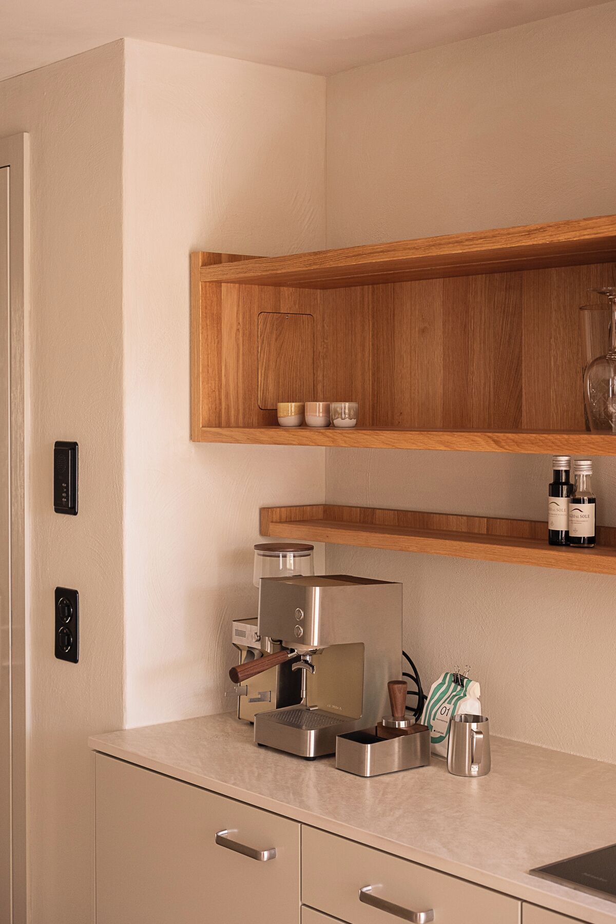 Eine moderne Küche mit integrierter Espressomaschine, Holzböden und einer Edelstahl-Kaffeemühle.