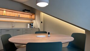 Une cuisine moderne avec une table ronde en bois, deux chaises de couleur turquoise et un luminaire suspendu.