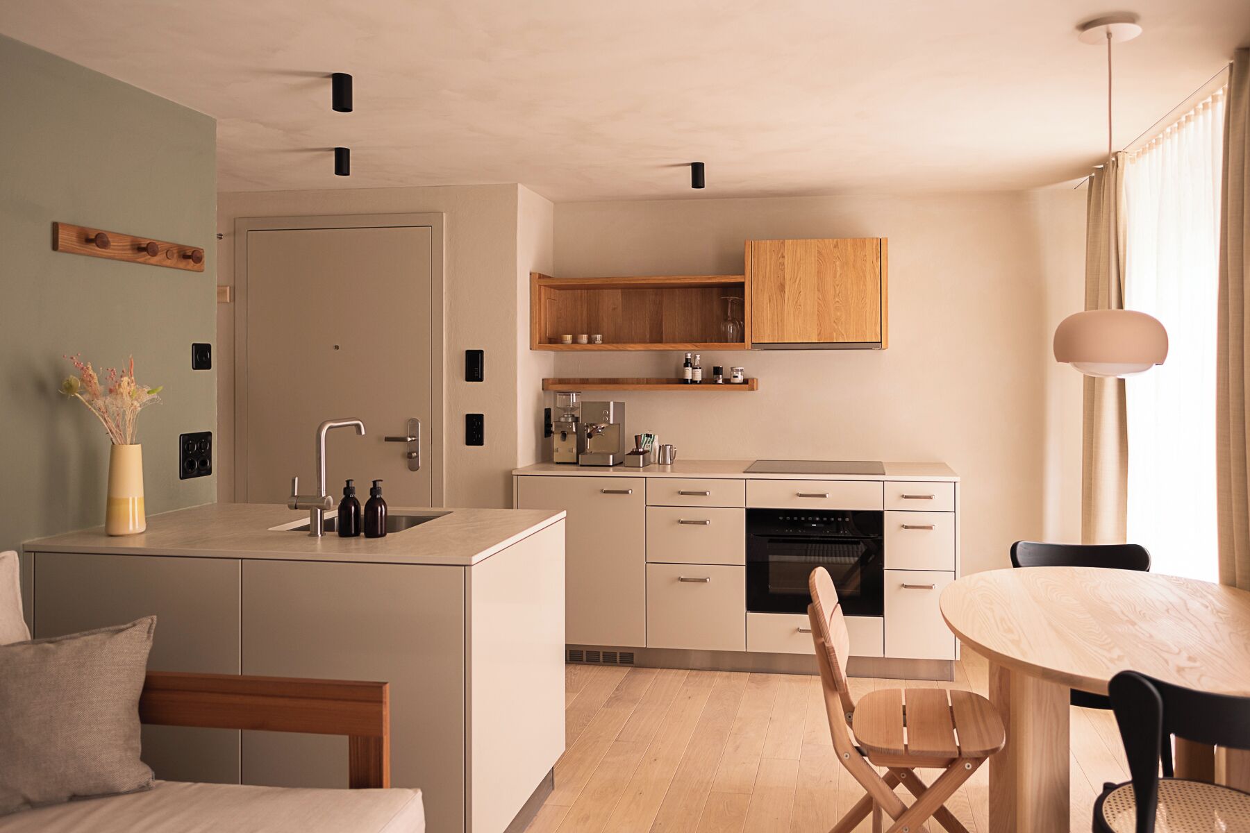 Eine moderne Küche mit einer zentralen Kochinsel, Holzschränken und einem Essbereich mit rundem Tisch und Stühlen.