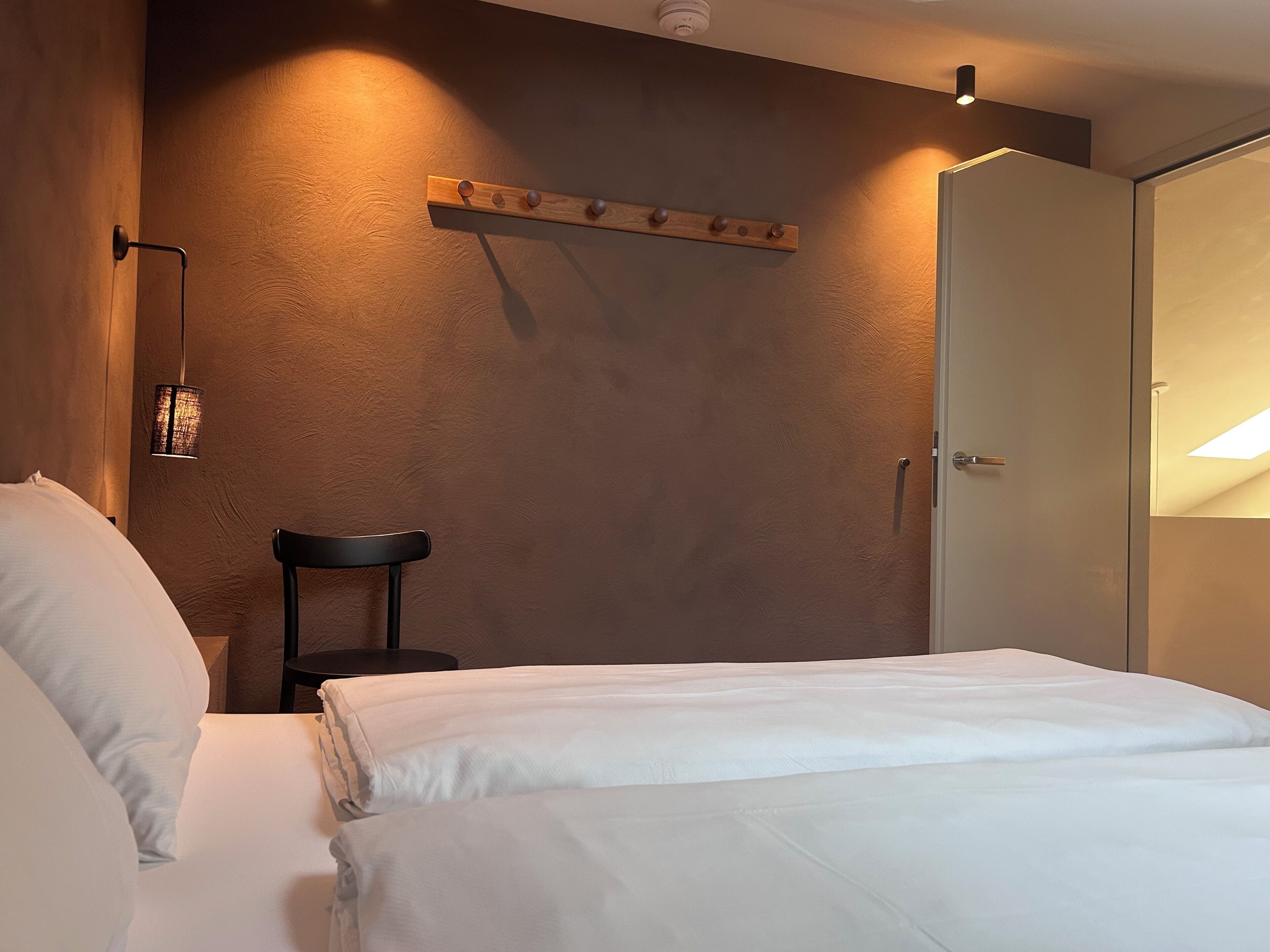 Une chambre d’hôtel avec un lit, une table de chevet, une lampe et une armoire.