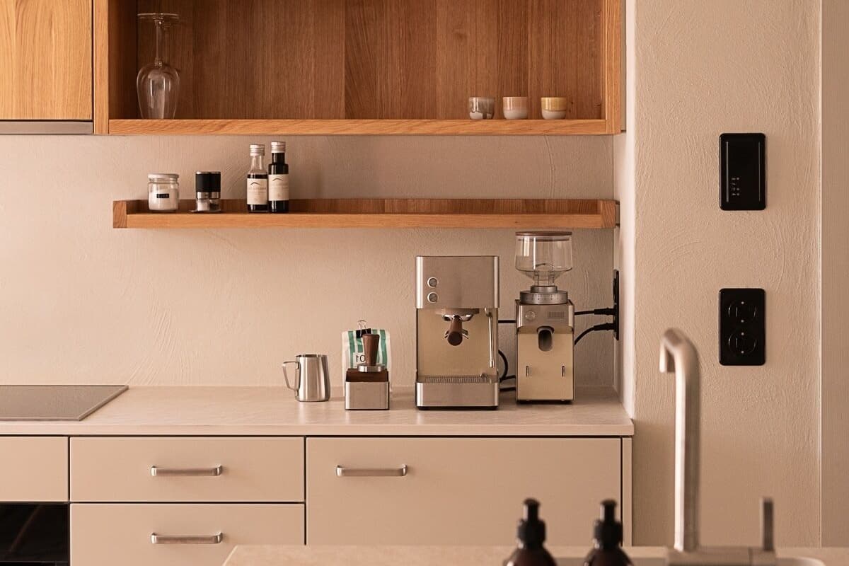 A modern kitchen with wooden cabinets, a coffee machine, and a built-in dishwasher.