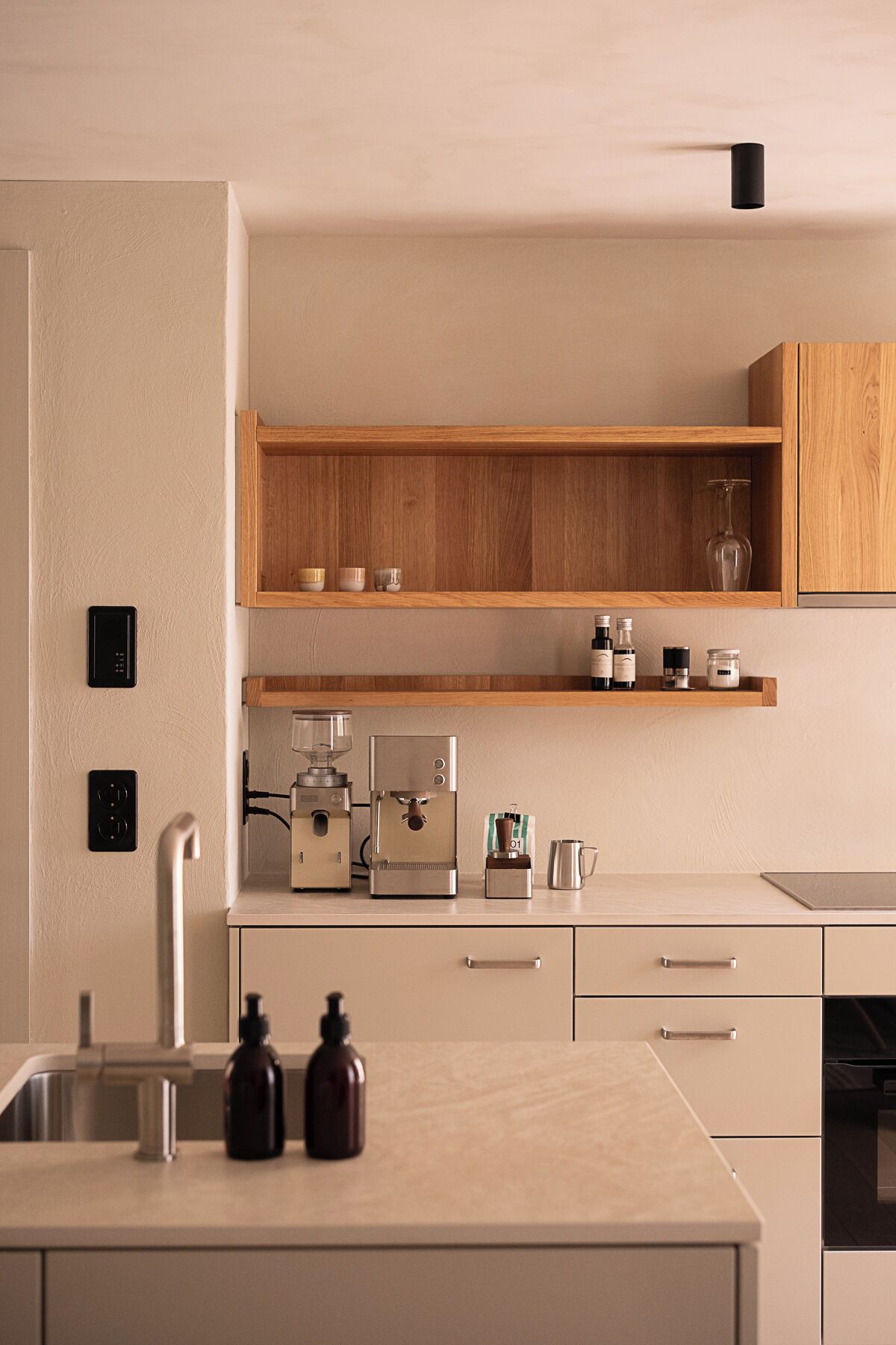 Een moderne keuken met een ingebouwde koffiemachine, houten planken en een minimalistisch design.