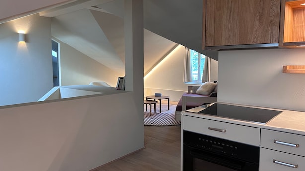 Une cuisine moderne dotée d’un four encastré et d’un coin repas avec une table et des chaises.