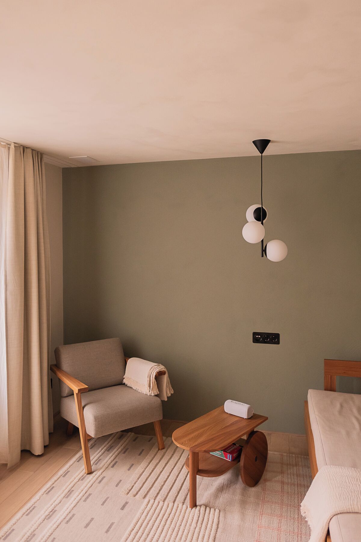 A cozy living room with a beige sofa, a wooden coffee table, and a hanging light fixture.