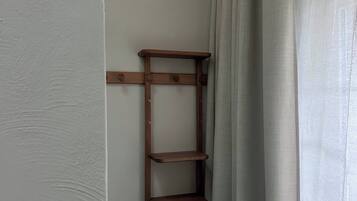 Une étagère en forme d’échelle en bois, adossée à un mur, avec une porte blanche et un rideau.