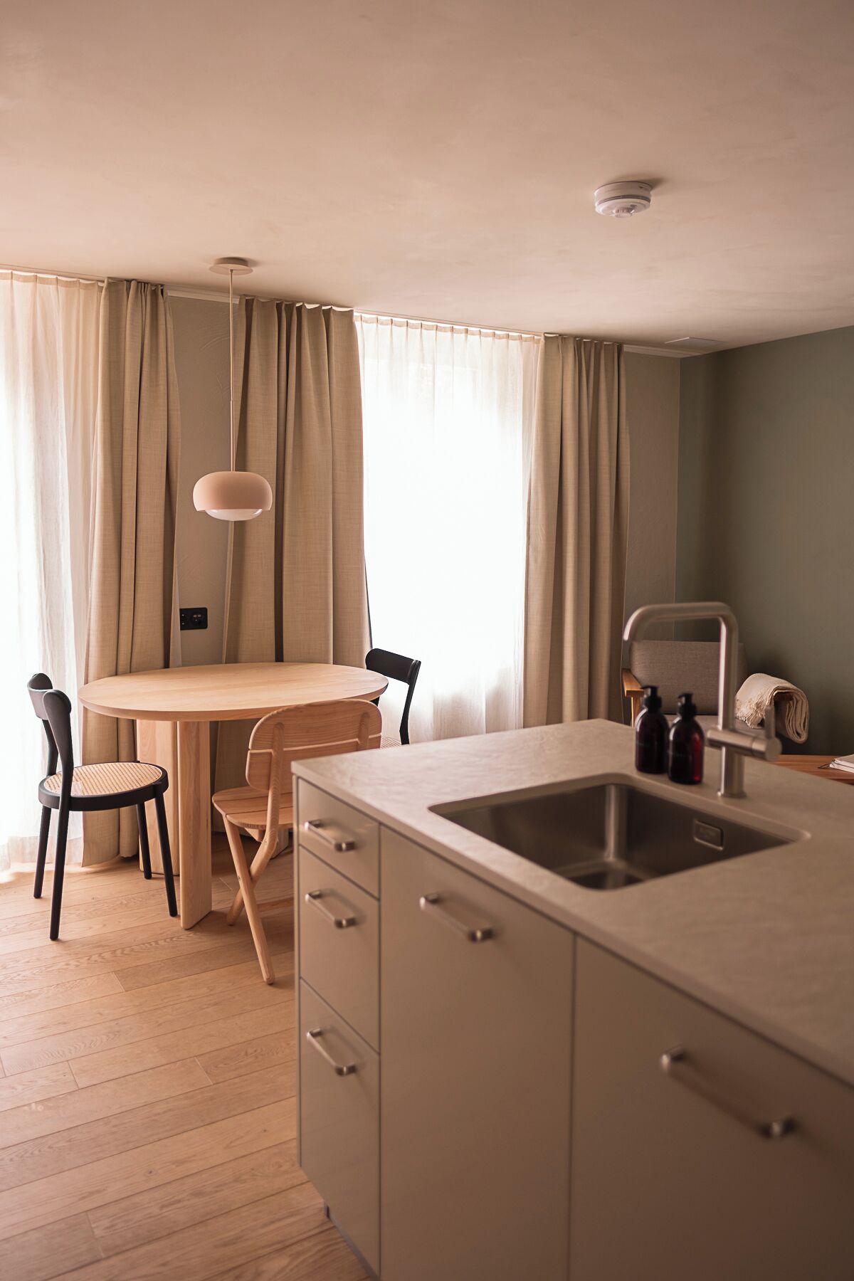 Une cuisine compacte comprenant un coin repas, un évier et un luminaire suspendu.
