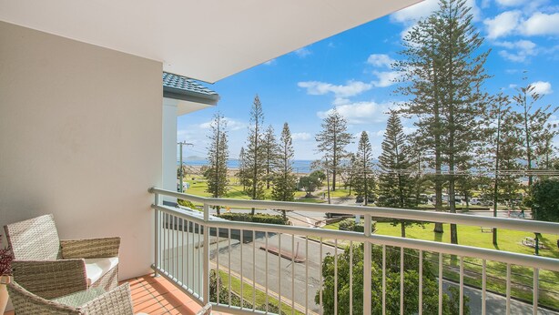 A balcony with a view of a park, trees, and a distant body of water. - Kirra On The Beach Apartments Unit 304 WIFI INCLUDED (Coolangatta)