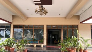 A hotel entrance with a staircase leading to the lobby, flanked by potted plants and a chandelier.