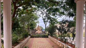 A pathway leading to a statue surrounded by trees and potted plants.