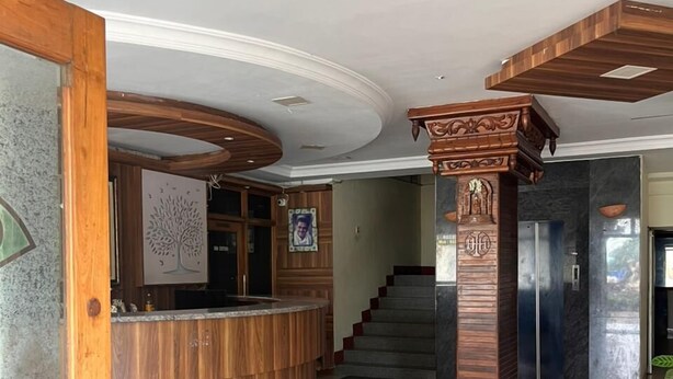 A reception area with a wooden reception desk, a staircase, and a decorative pillar.