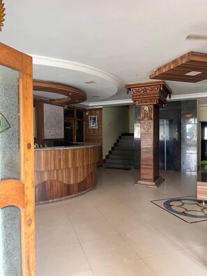 A reception area with a wooden reception desk, a staircase, and a decorative pillar.