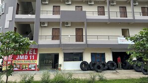 A multi-story hotel with balconies, air conditioning units, and a sign for AC rooms. - Hotel JMD 11 (Indore)
