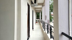 A corridor with air conditioning units, a tiled floor, and a railing. - Hotel JMD 11 (Indore)