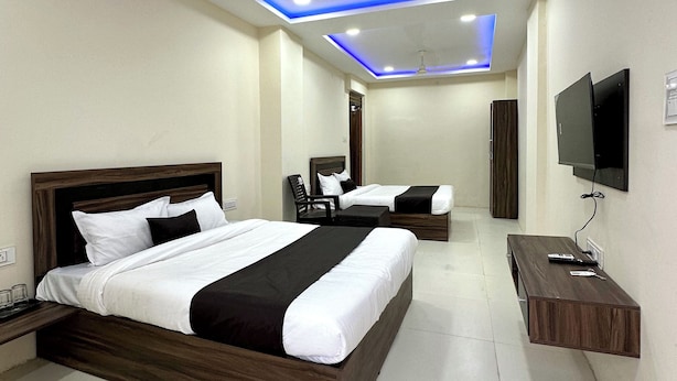 A modern hotel room with two beds, a TV, and a desk. - Hotel JMD 11 (Indore)