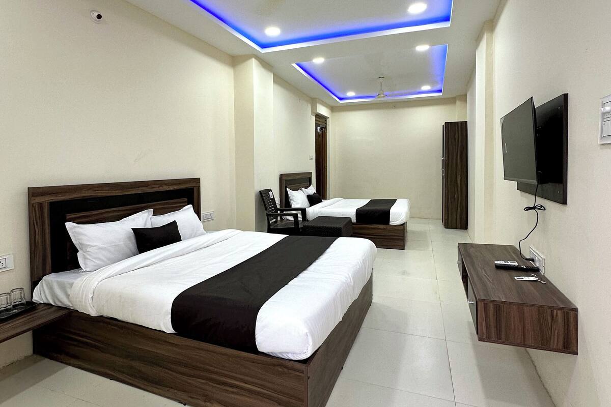 Quarto de hotel moderno com duas camas, uma TV e uma escrivaninha.