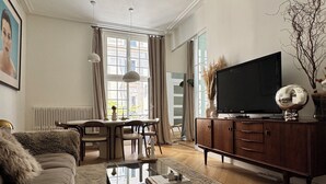 A spacious living room with a sofa, coffee table, and a television on a wooden cabinet.