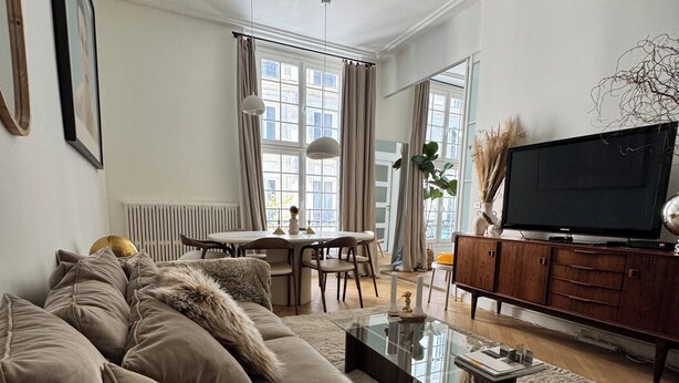 A modern living room with a sofa, a coffee table, and a television on a wooden cabinet.