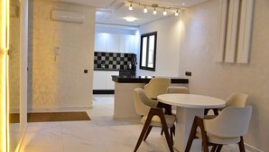 A modern kitchen with checkered backsplash, a dining area with a round table and four chairs, and an air conditioning unit on the wall.