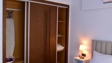 Una habitación de hotel con cama, mesita de noche con lámpara, armario y luz en el techo.