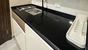 Eine moderne Küche mit schwarzer Arbeitsplatte, Spüle aus Edelstahl und Holzschränken.