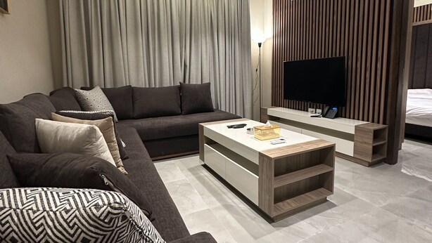 Ein modernes Wohnzimmer mit einem dunkelgrauen Sofa, einem Couchtisch und einem Flachbildfernseher.