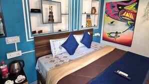 A bedroom with a bed, bedside tables, a wall-mounted air conditioner, and a painting. - The Pink Chapter Hostel, Jaipur (Jaipur)