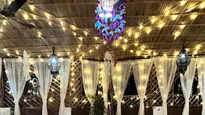 A room with a patterned floor, a central seating area with cushions, and a ceiling adorned with string lights and hanging lamps. - The Pink Chapter Hostel, Jaipur (Jaipur)