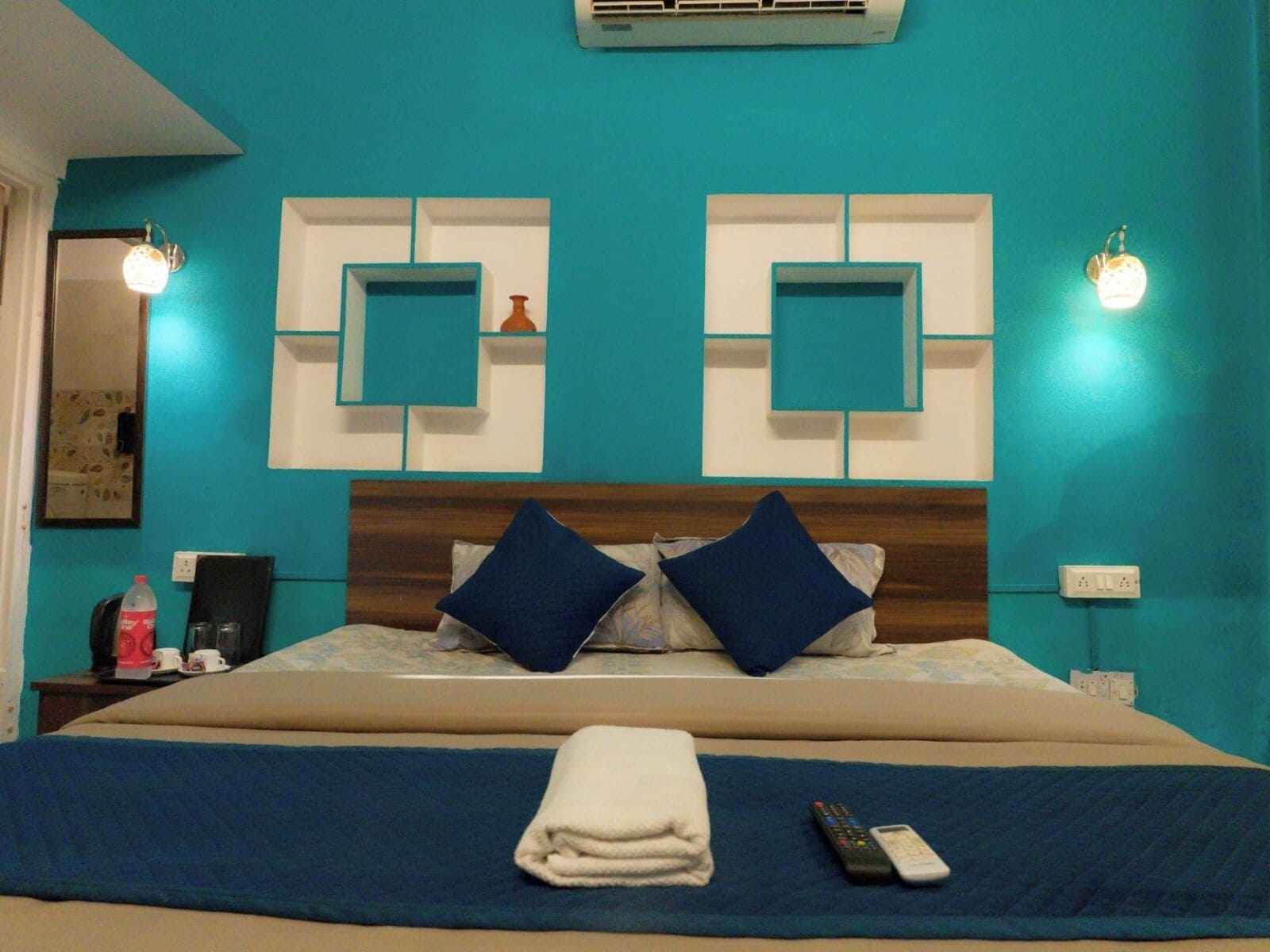 Une chambre d’hôtel avec un grand lit, deux lampes fixées au mur et un climatiseur fixé au mur.