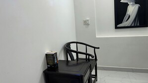 A room with a black chair, a small table, and a framed artwork on the wall. - T&M Homestay (Ho Chi Minh City)