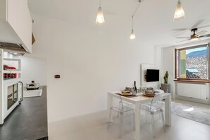 A modern kitchen with a built-in oven, a dining area with a table and chairs, and a large window with a view of the mountains.