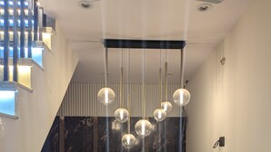 A modern interior with a marble reception desk, pendant lights, and a ceiling fan. - Avanti inn (Ujjain)