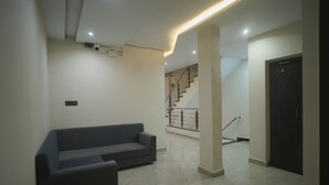 A modern interior with a grey sofa, a staircase, and a black door. - Avanti inn (Ujjain)