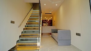 A modern interior with a staircase, a sofa, and a ceiling fan. - Avanti inn (Ujjain)