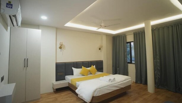 A modern hotel room with a bed, bedside table, wardrobe, and a ceiling fan. - Avanti inn (Ujjain)