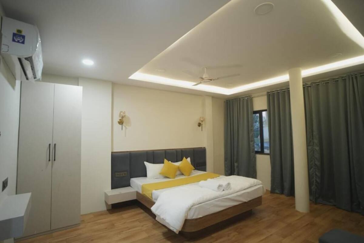 A modern hotel room with a bed, bedside table, wardrobe, and a ceiling fan.