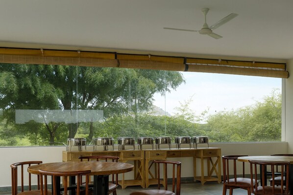 A room with a large window, a ceiling fan, and a wooden table with chairs.