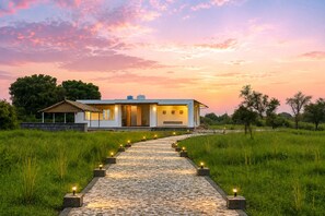 Una casa moderna con un camino de piedra que lleva a la entrada, rodeada de follaje.