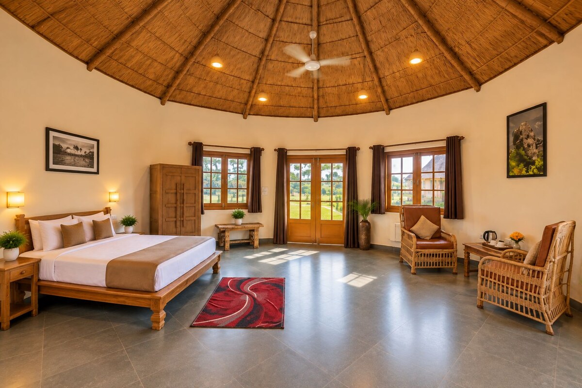 A spacious room with a bed, a desk, wicker furniture, and a ceiling fan.