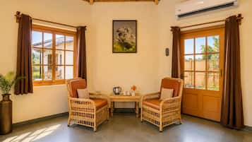 Una habitación con dos sillones de mimbre, una mesa con una tetera y un cuadro en la pared.
