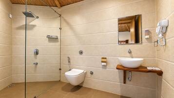 A modern bathroom with a glass-enclosed shower, a toilet, a sink with a wooden countertop, and a mirror above the sink.