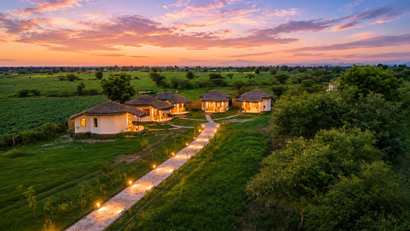 A row of traditional houses with a pathway leading to them, surrounded by lush greenery.